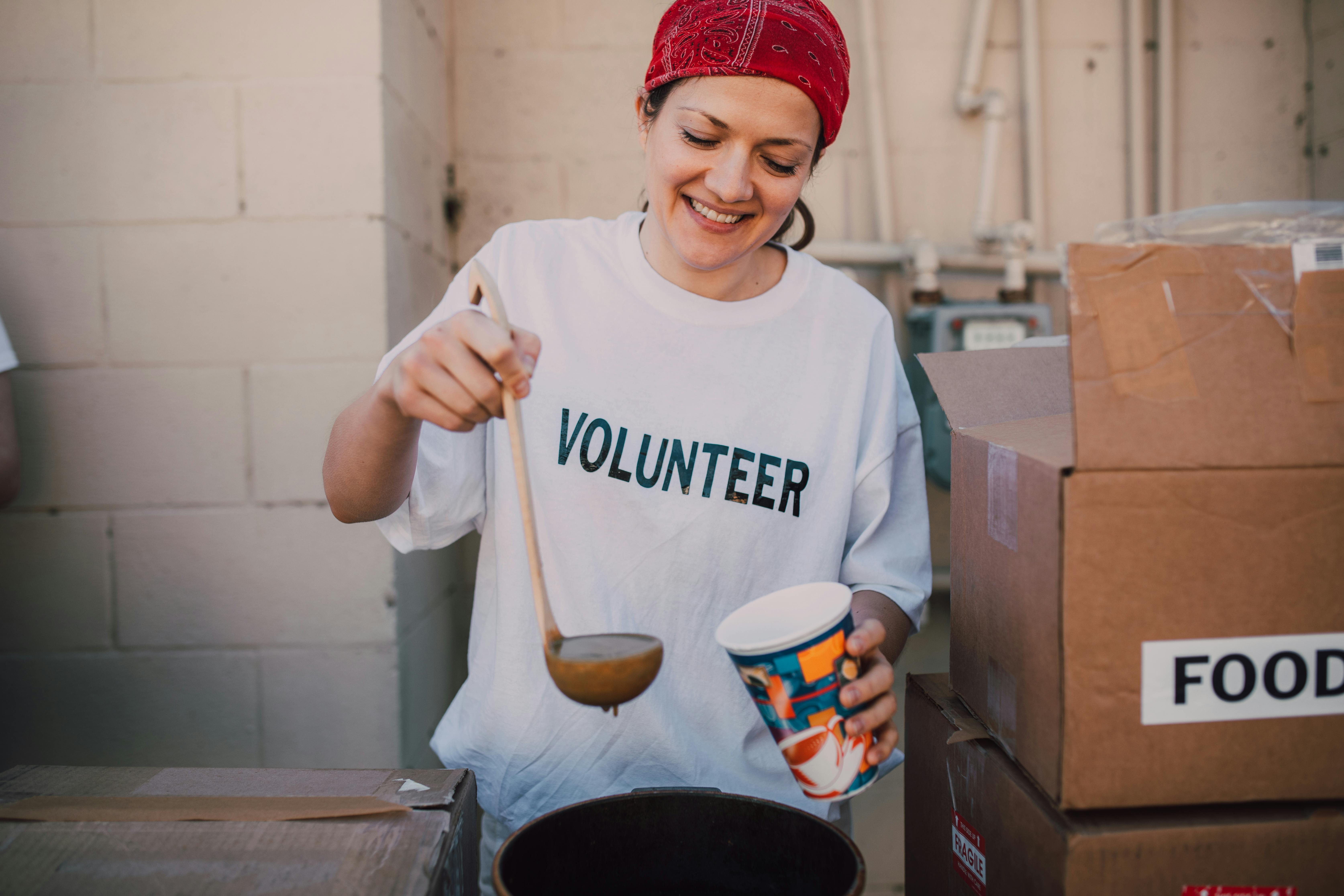 Volunteering woman pouring soup into cup for the needy